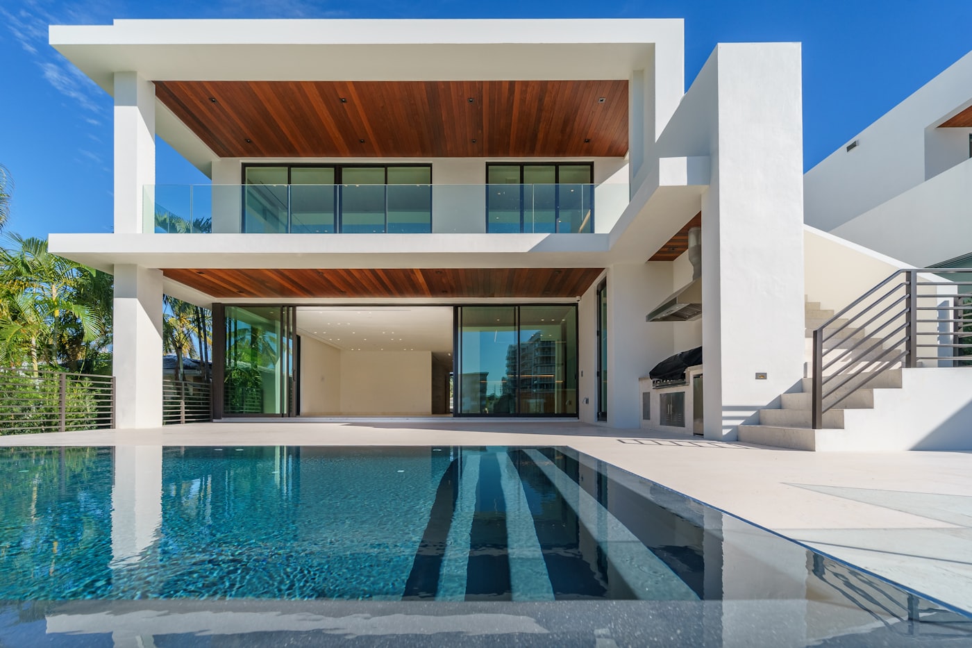 Casa moderna de obra nueva con grandes puertas correderas de vidrio abiertas al jardín y piscina