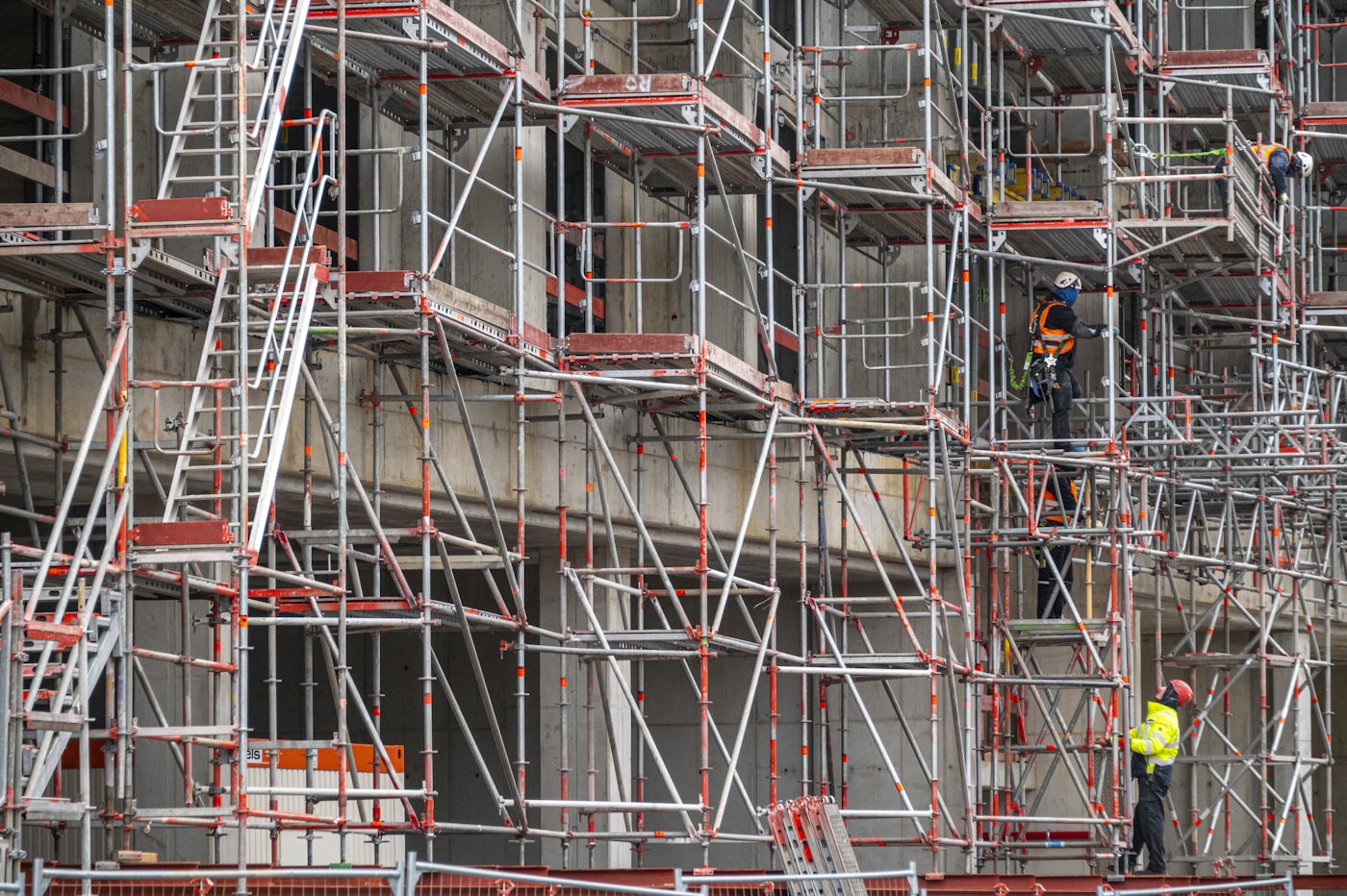 Fachada de un edificio en rehabilitación con andamio montado y operarios trabajando
